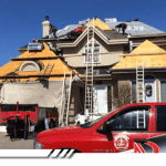 Équipe de couvreurs remplaçant la toiture d’une grande maison résidentielle