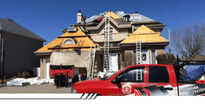 Équipe de couvreurs remplaçant la toiture d’une grande maison résidentielle